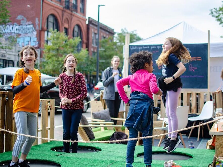 A group of kids jump on trampolines in Central Square during PARK(ing) Day