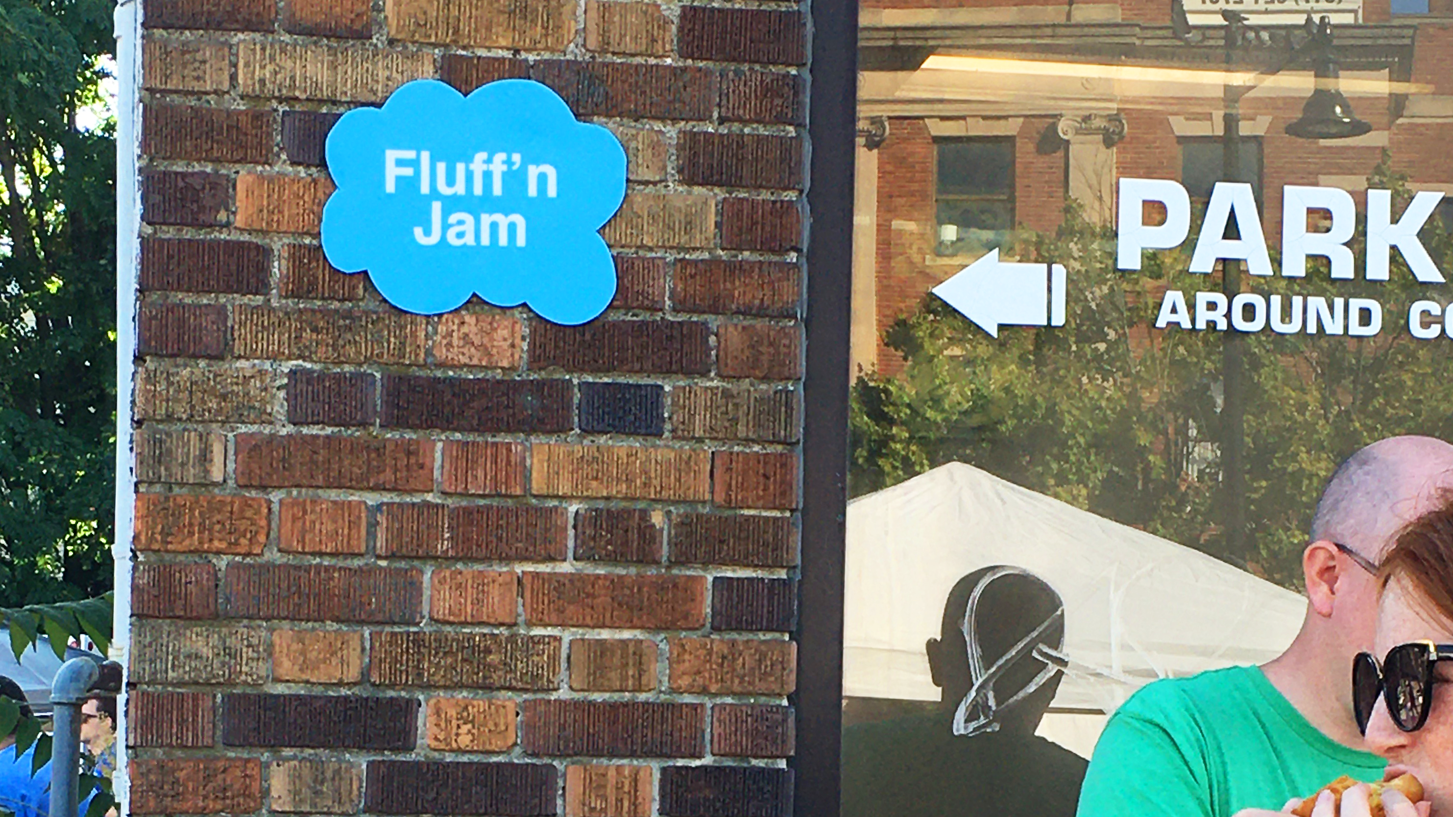 A blue cloud-shaped sign on a brick wall with the text "Fluff'n Jam"