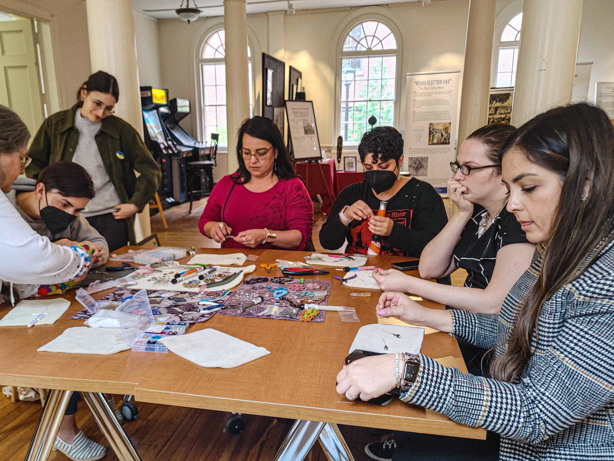 People sit around a table hand crafting with beads.