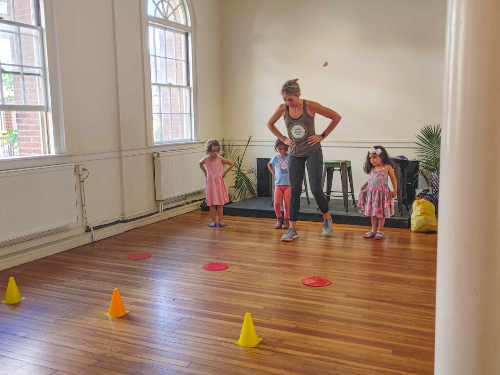 A woman leads three children in a play exercise in the Old Town Hall.