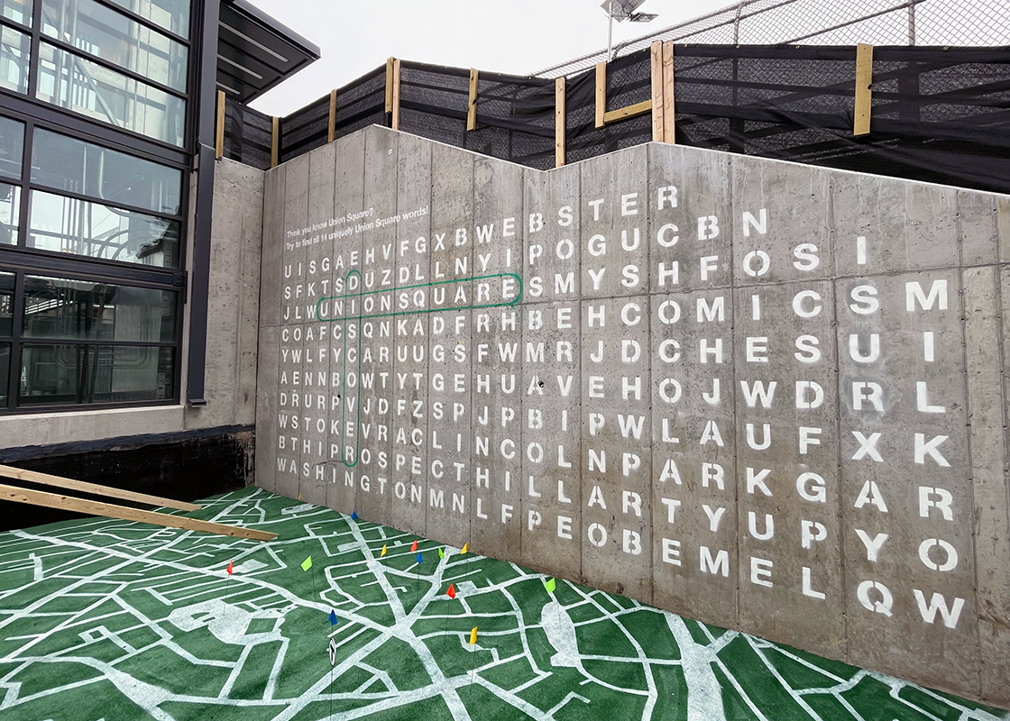 Broader image of the crossword puzzle and painted map on the ground with flags.