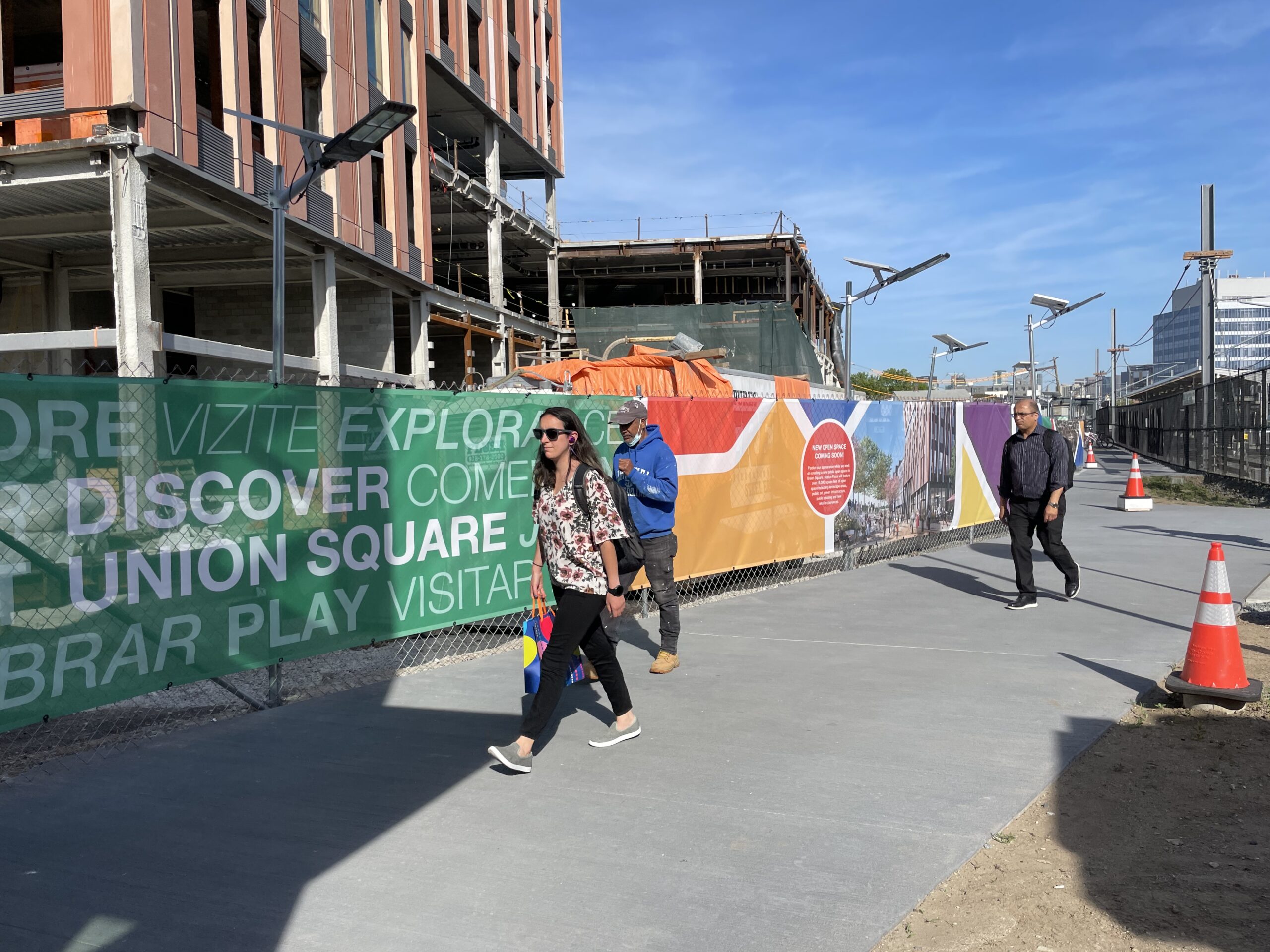 People walk in front of the Discover Union Square scrim.