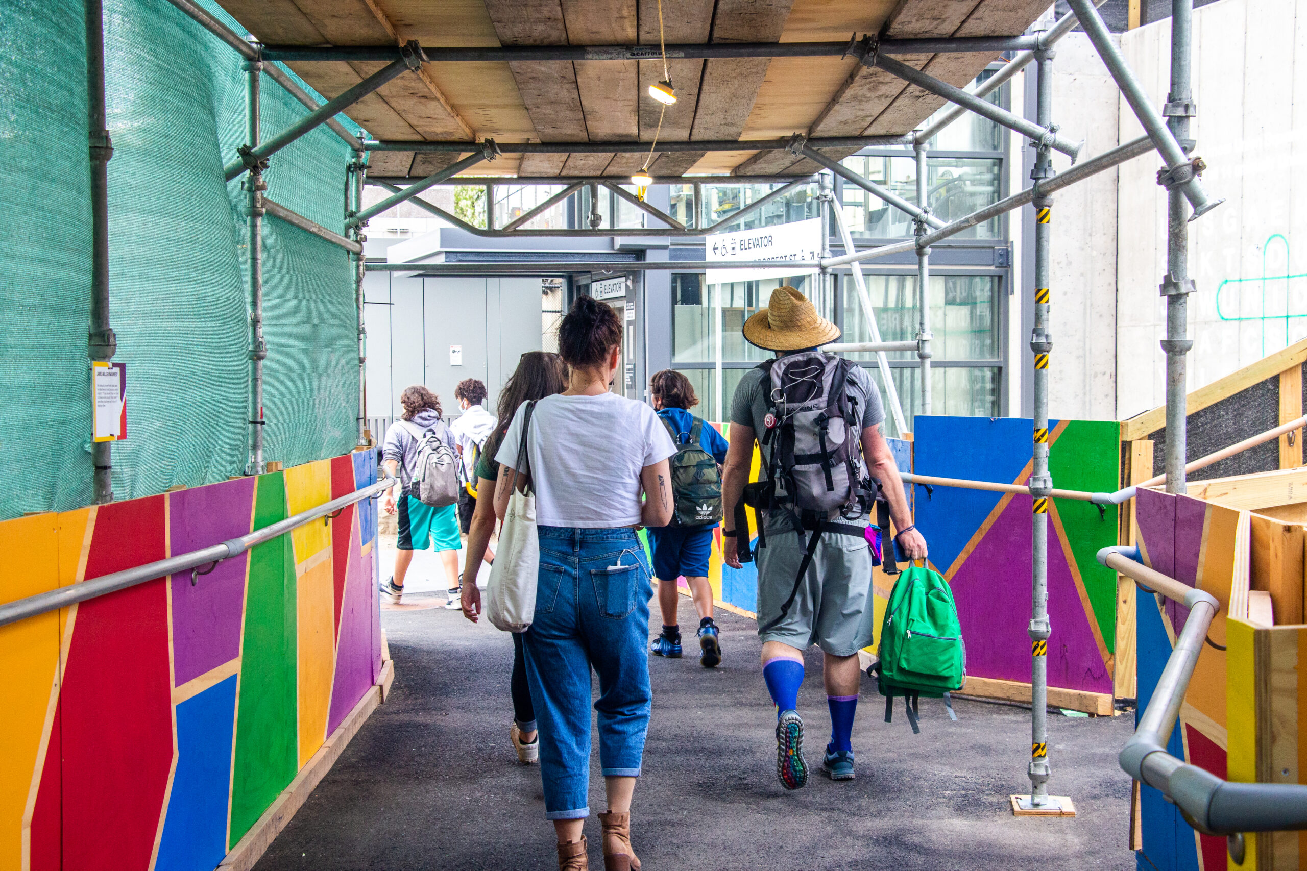 People walk away from the camera along a walkway with brightly-colored sides