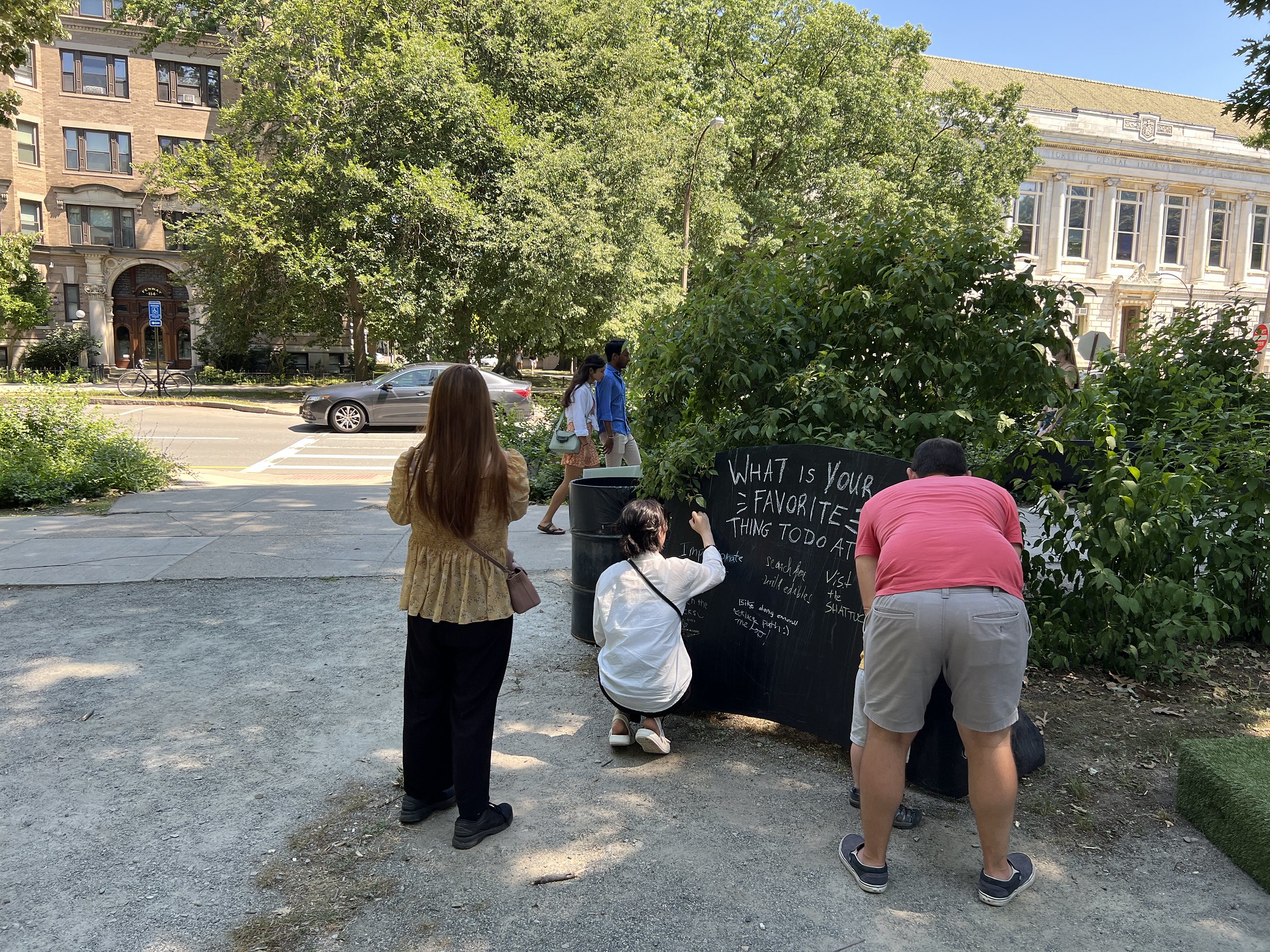 People write on a chalkboard answering the question: What is your favorite thing to do in the park?