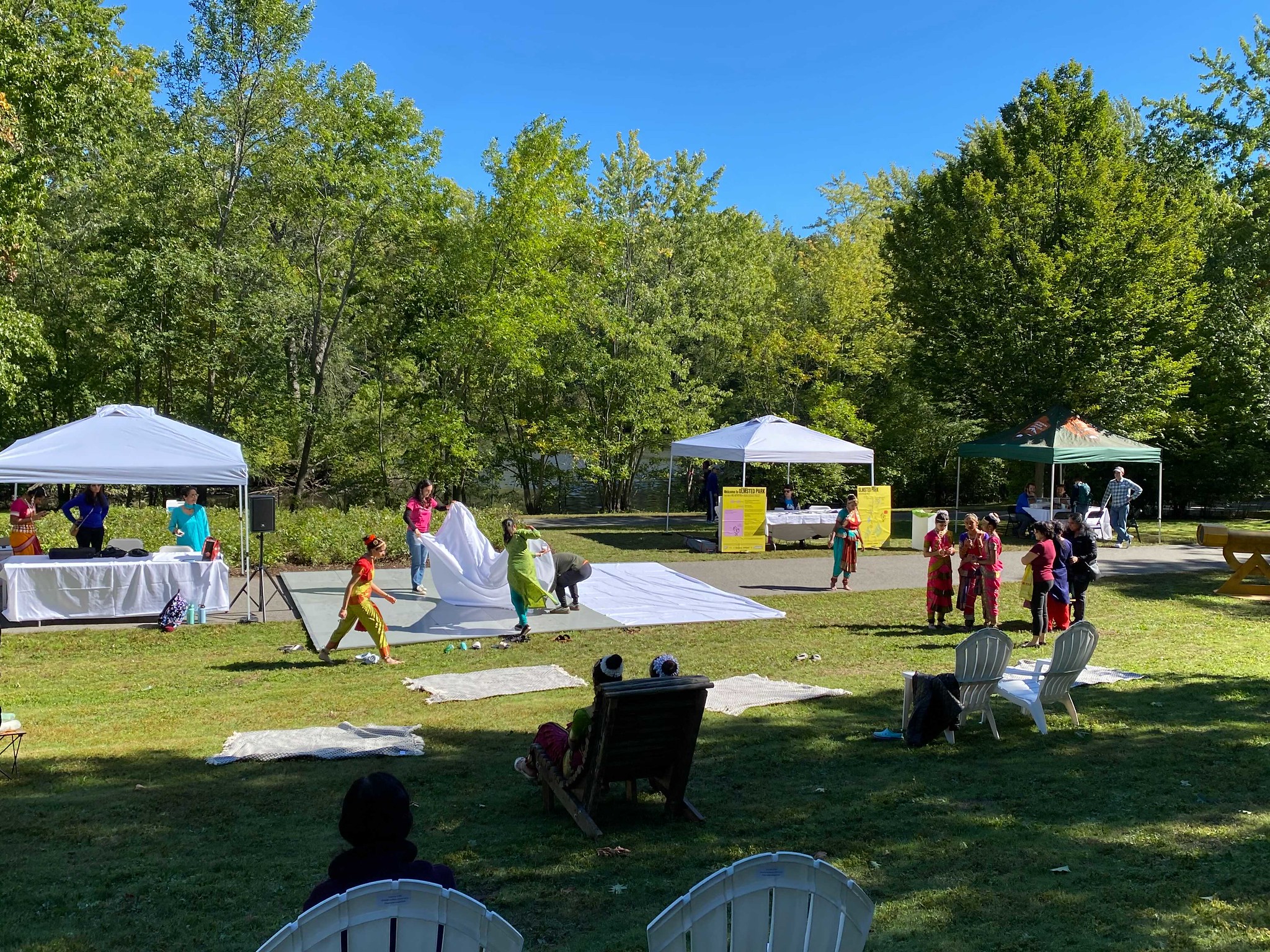 People setting up a dancefloor with tents in the background