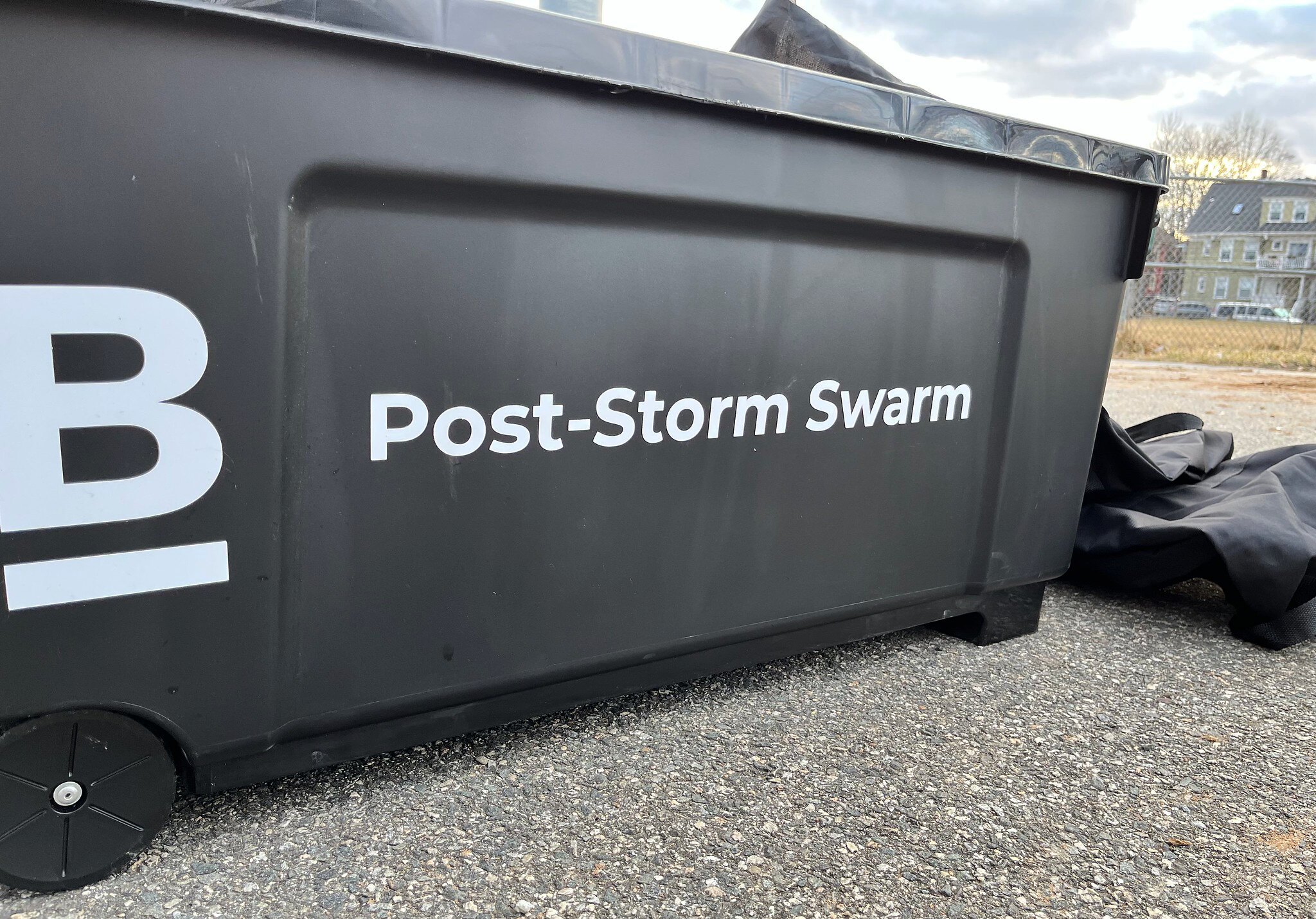 A large black bin sits on the ground marked with the City of Boston logo and a label that reads "Post-Storm Swarm"