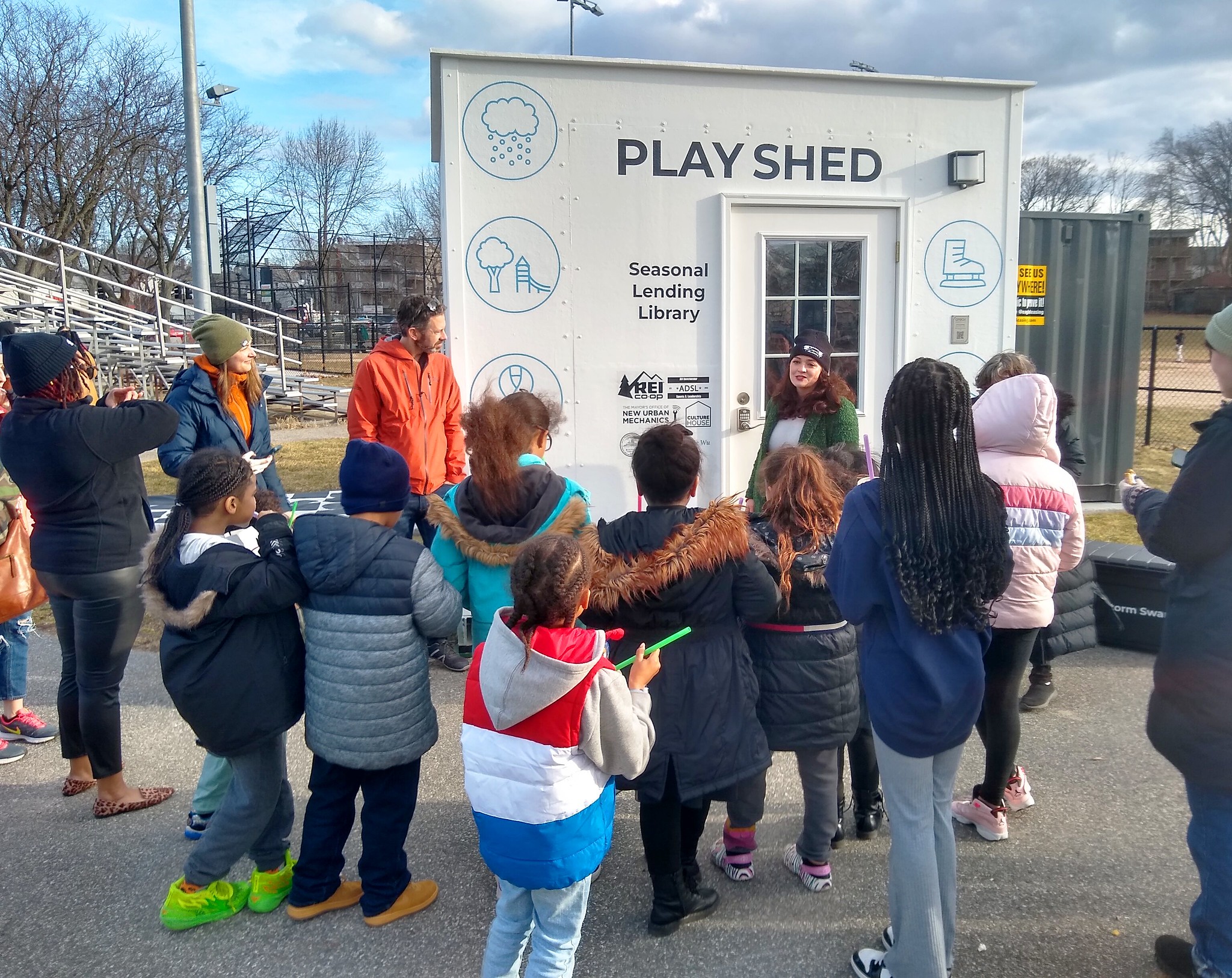 A member of MONUM gives a short speech about the play shed opening to a crowd of children.