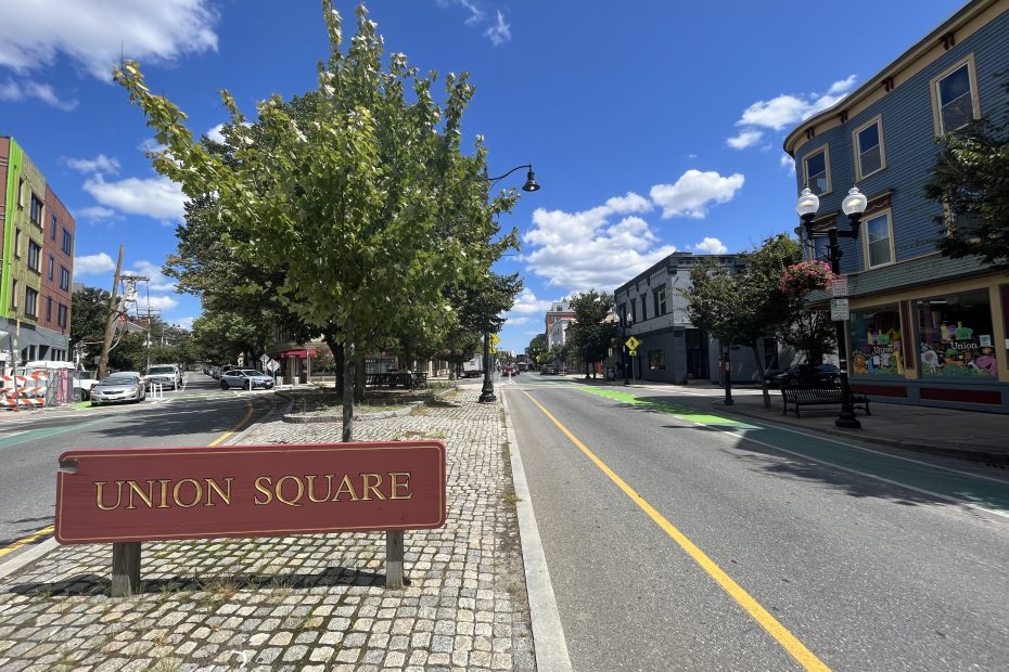 A red sign reading "Union Square" sits on a median in front of a tree