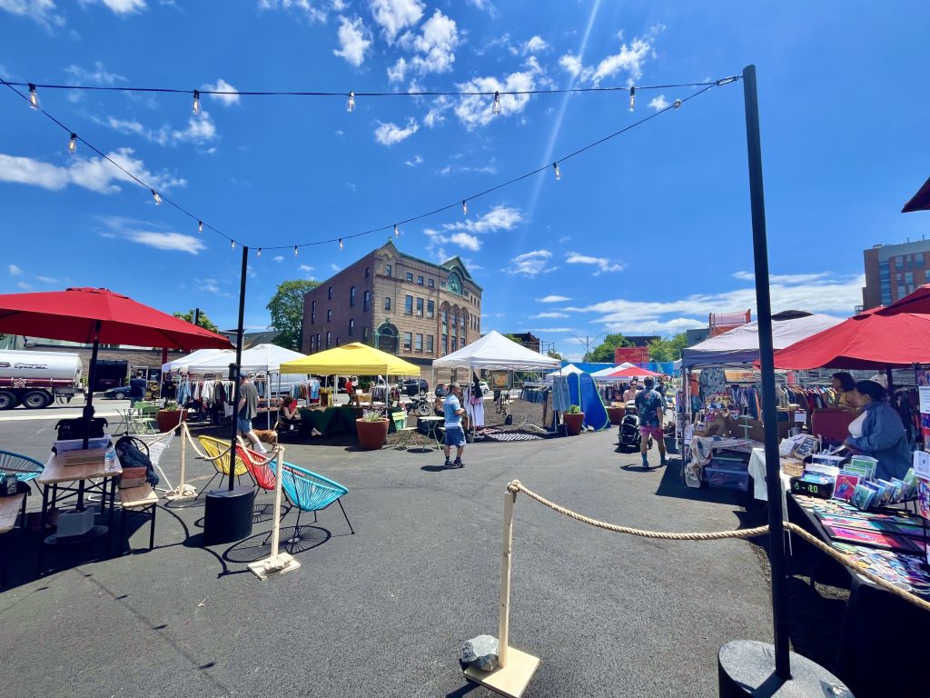Vendor market at Gilman Square showing tents and a beer garden.