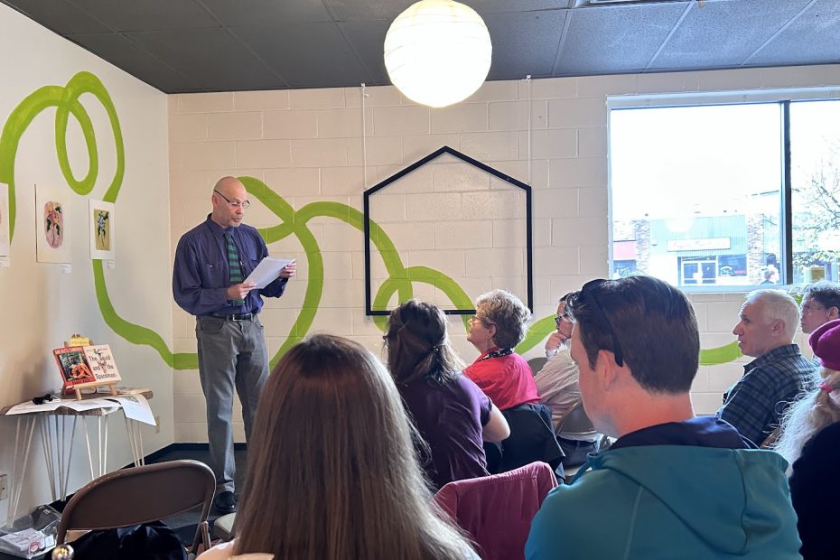 Man standing on a stage reading a poem to an audience