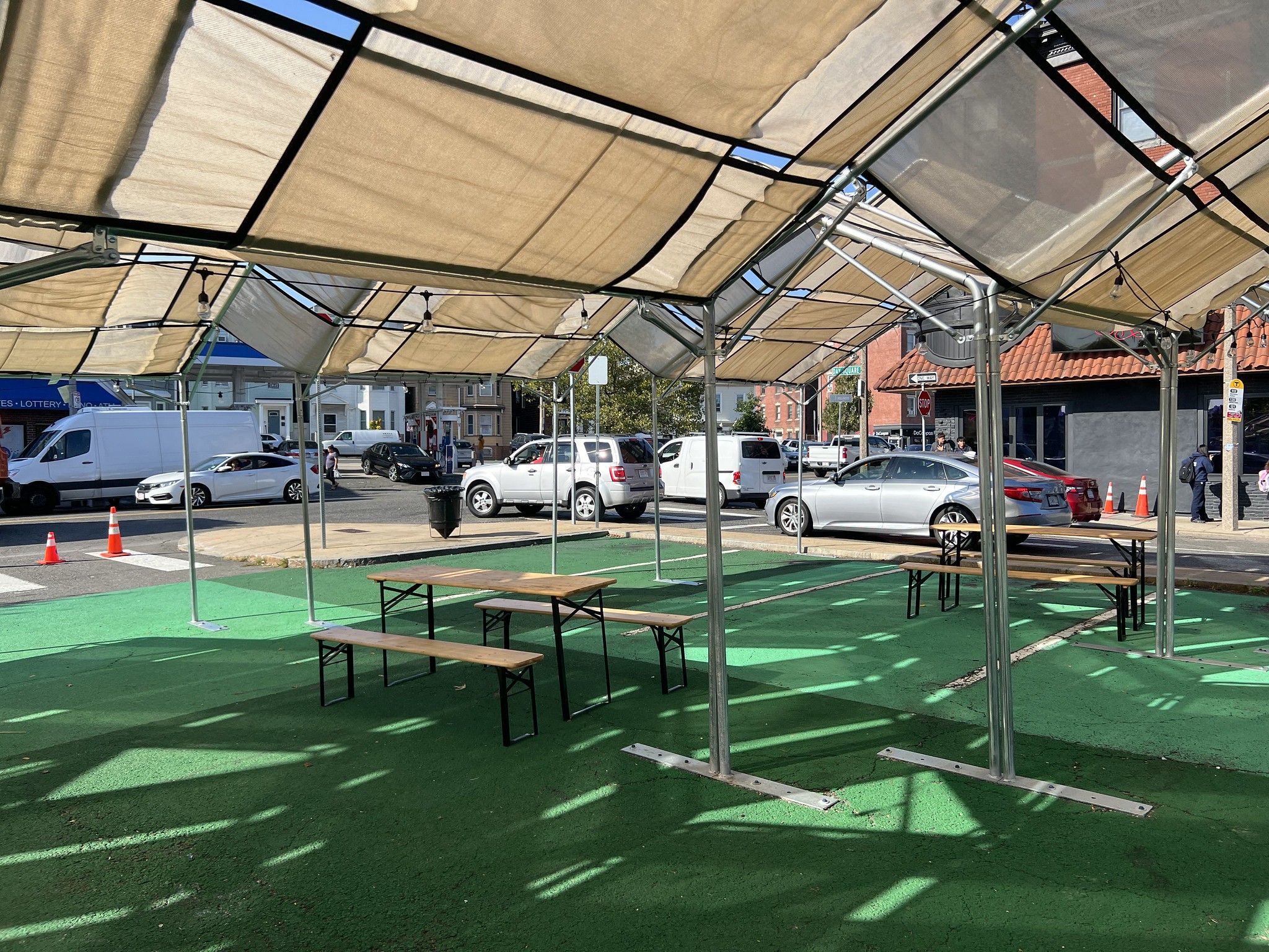 Picnic tables sit underneath a tan shade structure.