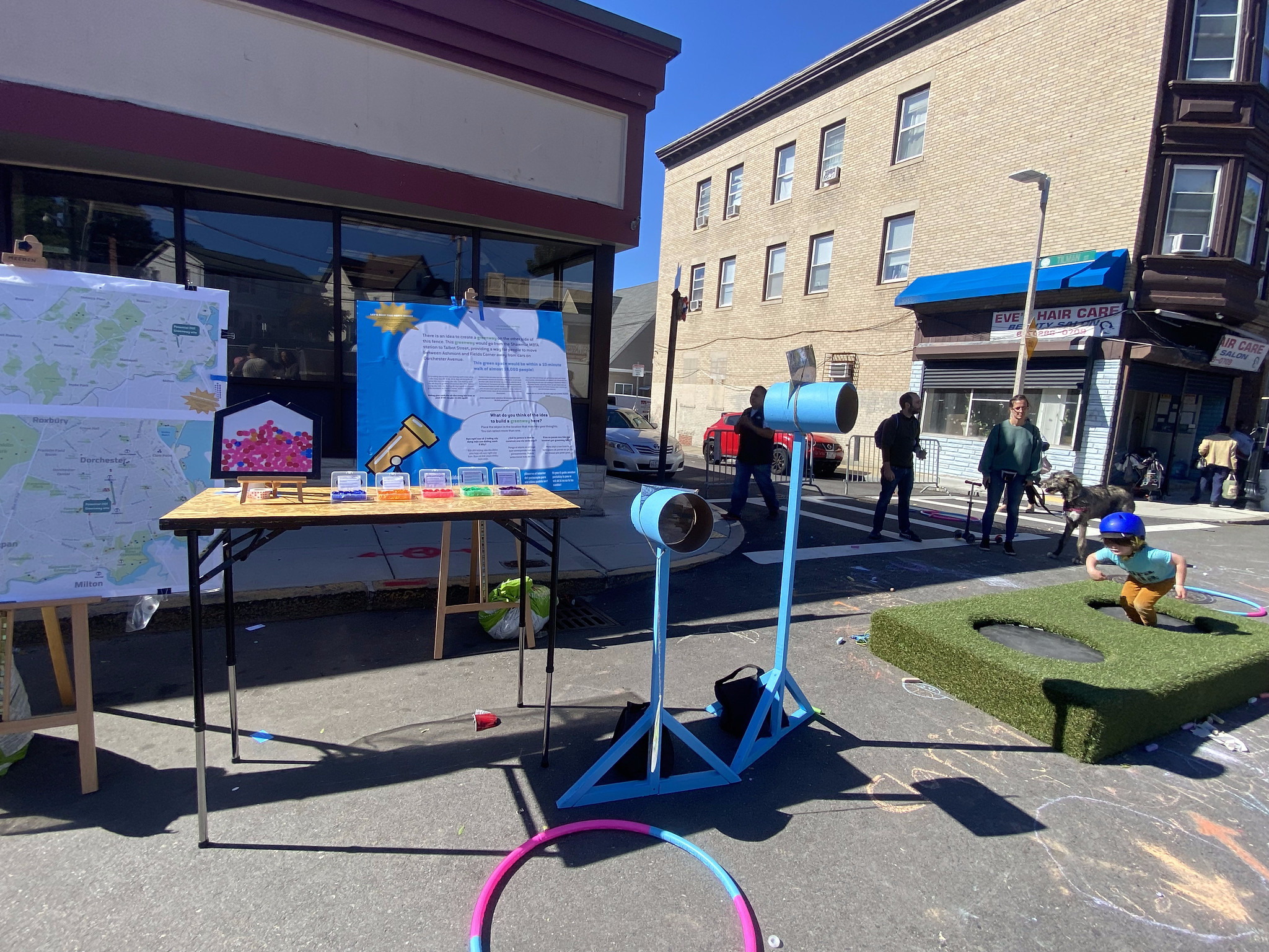 Informational posters stand behind two blue periscopes and a trampoline