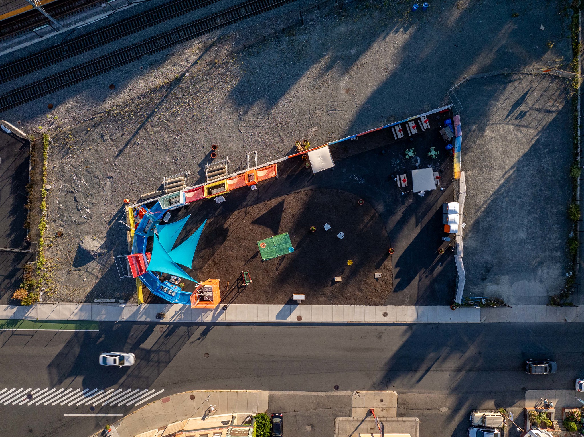 Top-down drone image of the full Gilman Square lot, with colorful scrim and shade sails