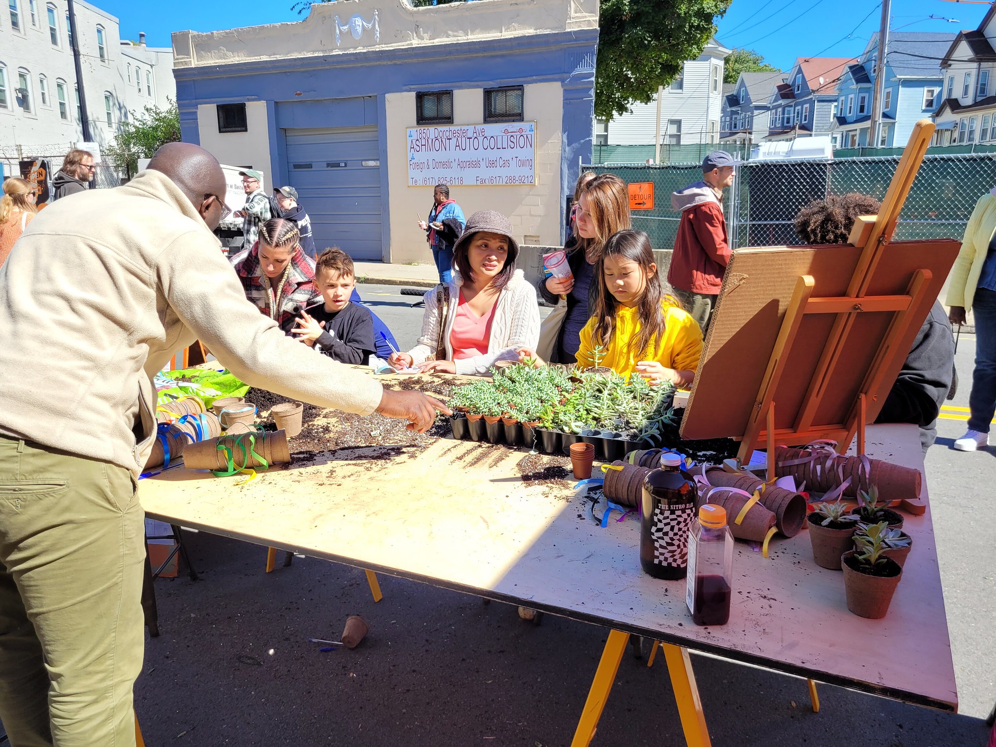 A man hands out plants over a table to people passing by