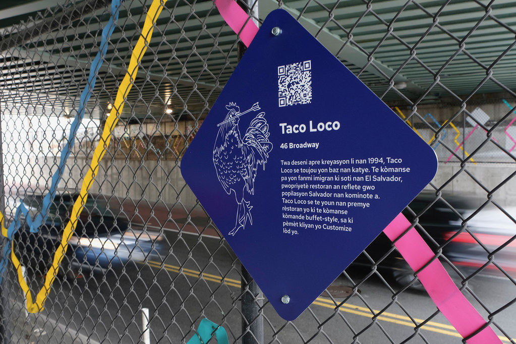 A diamond shaped sign with an image of a chicken on it describes Taco Loco a long-standing Salvadoran restaurant in East Somerville