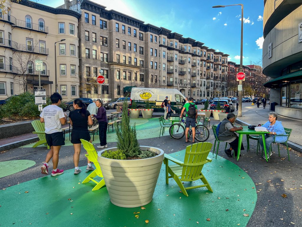 People walk around a plaza filled with chairs and planters