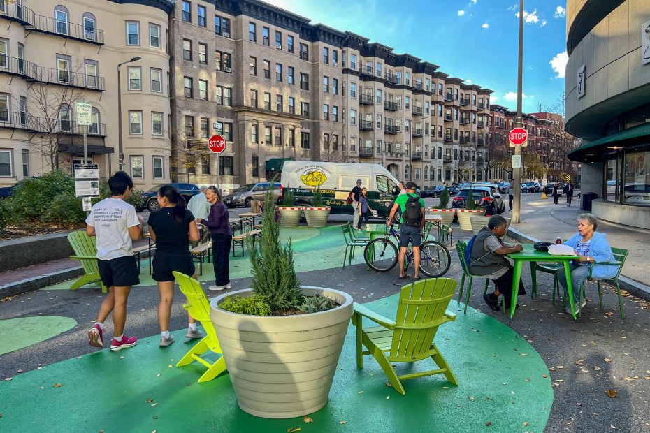 People walk around a plaza filled with chairs and planters