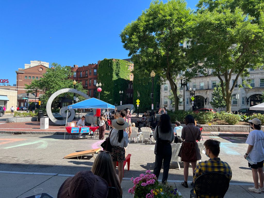 People stand and watch a music performance on a closed street