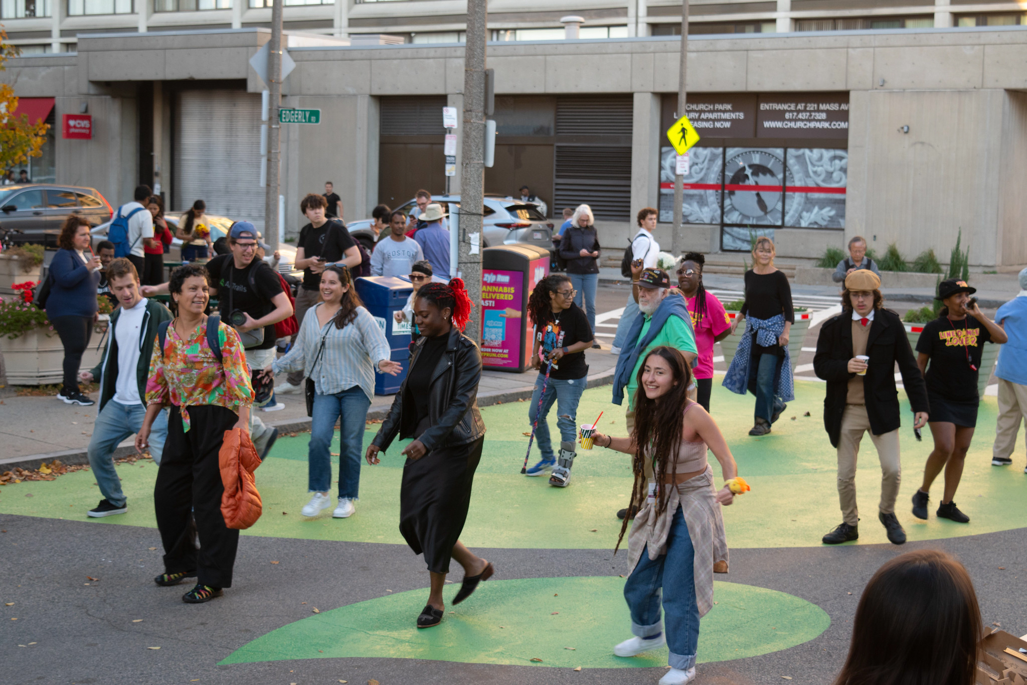 A group of people dance to the Cupid Shuffle on a painted street.