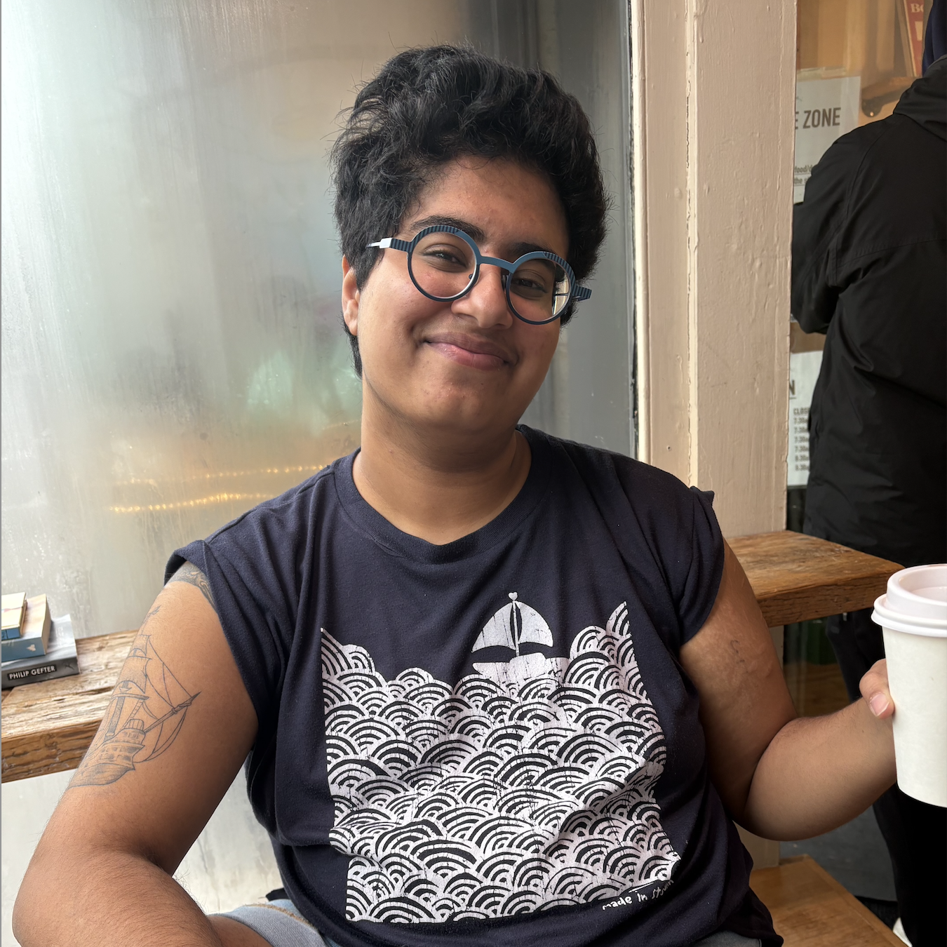 Amaal smiling and holding a cup of coffee
