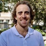 Josh smiling in front on a background of greenery